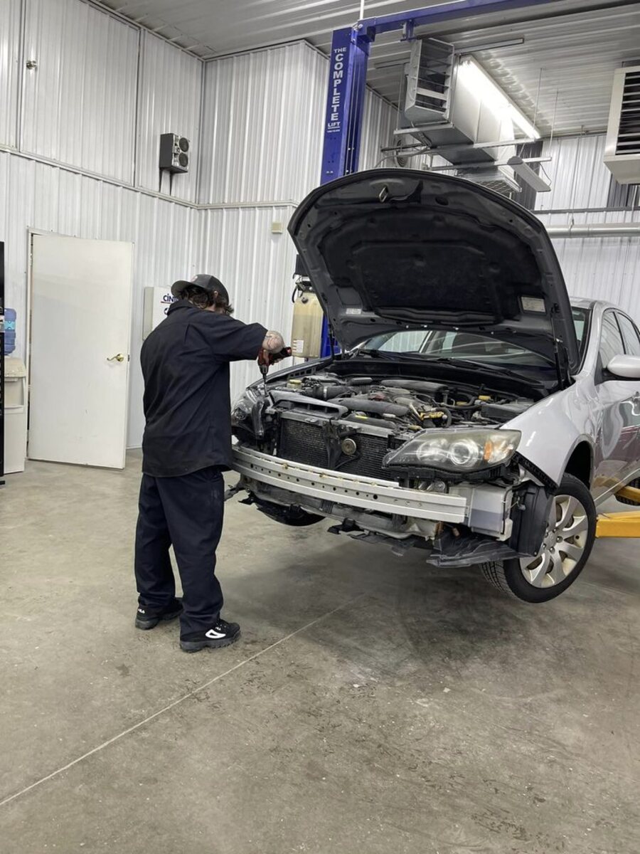 A technician working under the hood during a collision repair